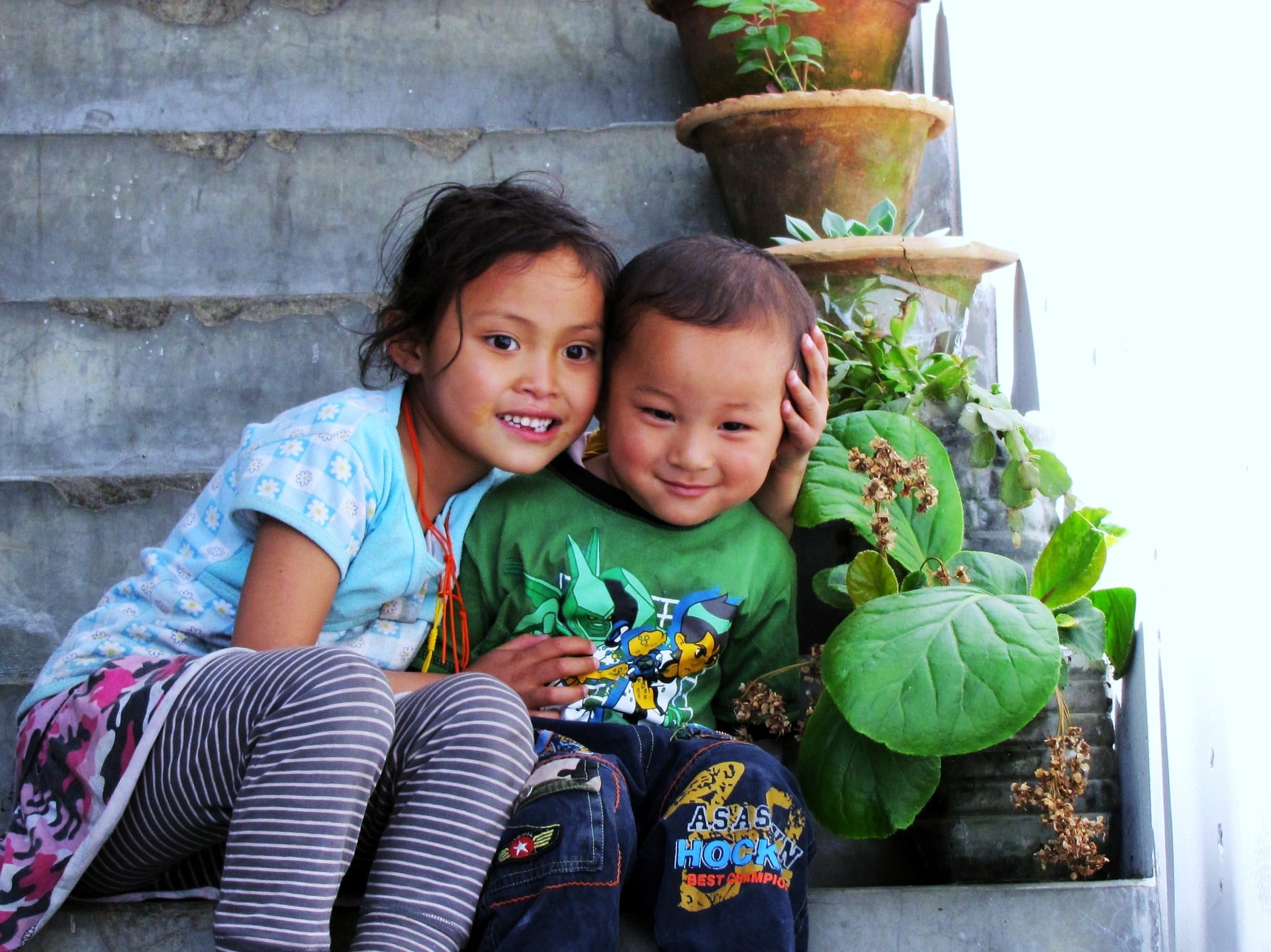2 enfants qui sourient assis sur les marches