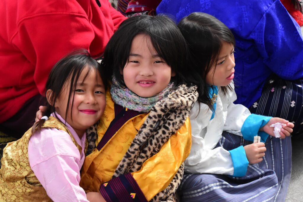 3 enfants bouthanais heureux qui sourient qui représente le Bonheur National Brut